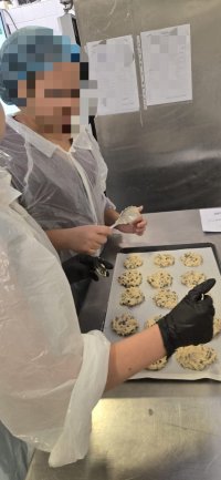 Cette photo représente un élève devant une plaque de cookies non cuits.