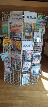 Cette image montre un ensemble de périodiques exposés sur des grilles disposées en rond. Ils sont triés par thématiques, ici : Economie/politique, culture et société