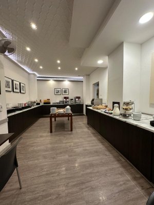 Cette image montre la salle du buffet du petit déjeuner : de grands comptoirs longent les murs avec déposés dessus des viennoiseries, des boissons chaudes et froides...