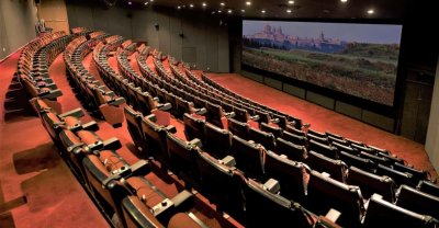 Cette image montre l'intérieur du théâtre : ls sièges sont en arc de cercle, nivelés, et font face à un grand écran comme au cinéma.