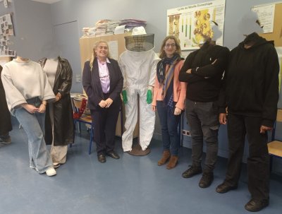 Cette photo montre des élèves et des professeurs prenant la pose autour d'un mannequin vêtu d'une combinaison d'apiculteur